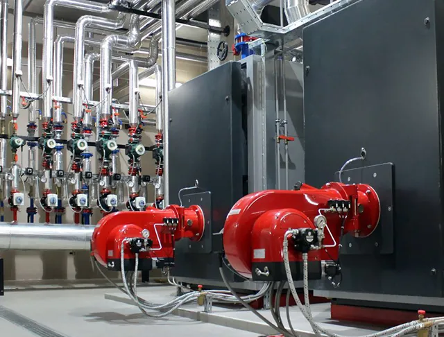 Commercial boiler system with red burners and extensive piping.